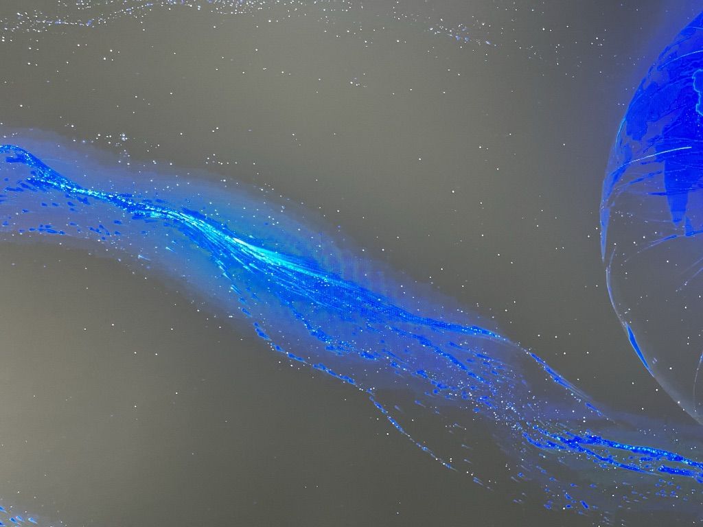 A river of blue light and points like stars flowing towards a glowing sphere